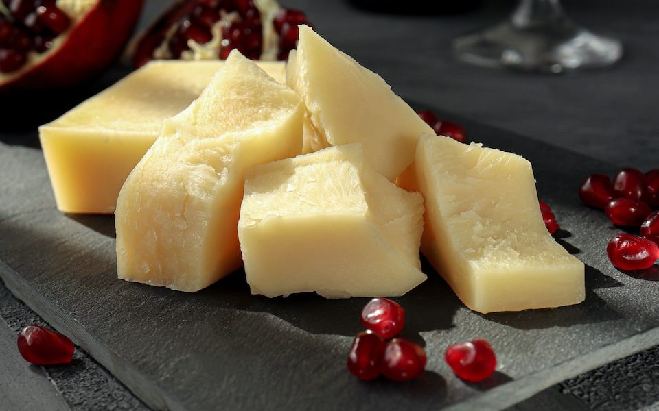 sliced cheese on black plate beside wine glass
