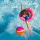 girl in blue tank top and blue shorts holding pink inflatable ring on water