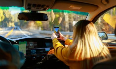 a woman driving a car with a cell phone in her hand