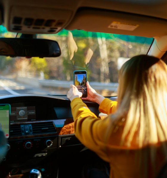 a woman driving a car with a cell phone in her hand